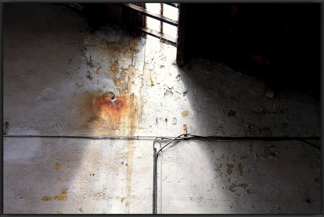 Lichtstrahl auf einer verwitterten Wand in einer Industriehalle